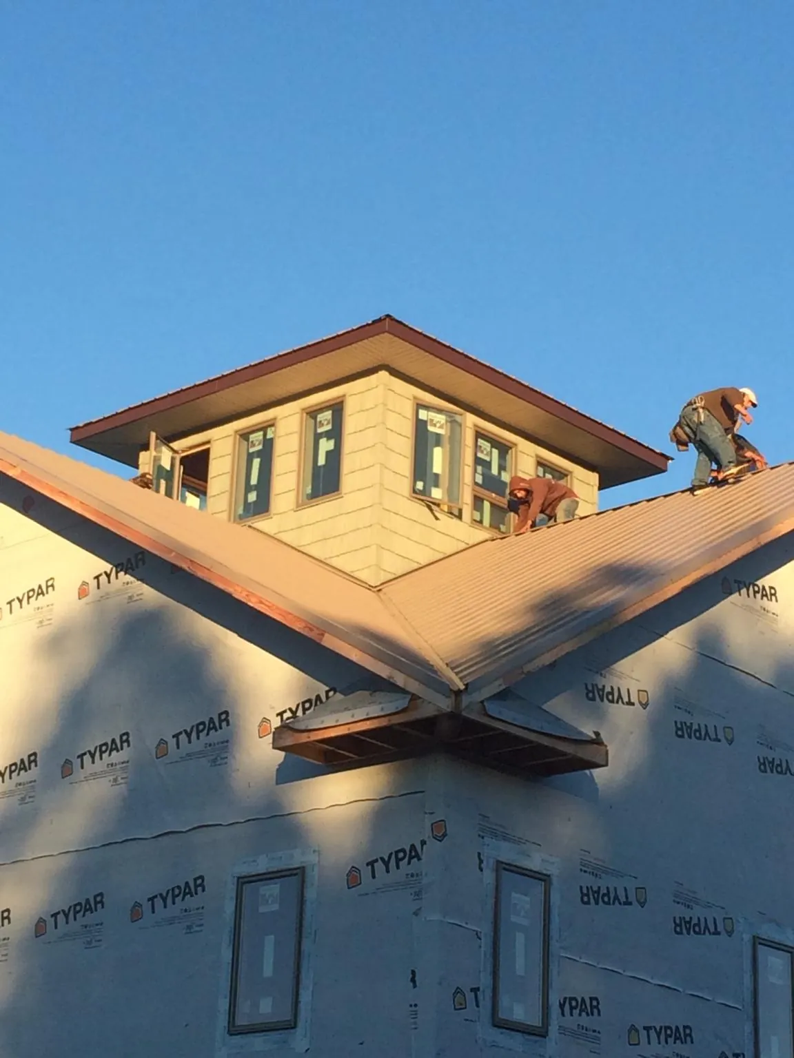 Roofers working around a rooftop cupola on a new metal roof at sunset — Roof Waterproofing in Somerdale by Roofing Brothers